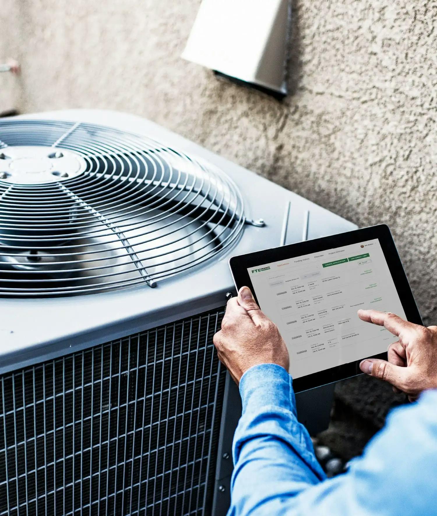 HVAC Technician holding a tablet next to an air conditioning unit.